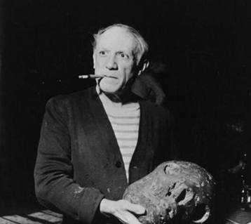 Picasso smoking a cigarette looking at a large stone